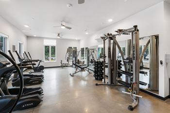 A gym with a variety of equipment including treadmills, stationary bikes, and weight machines.
